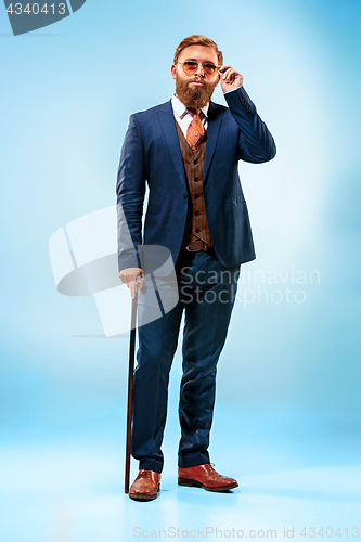 Image of The barded man in a suit holding cane.