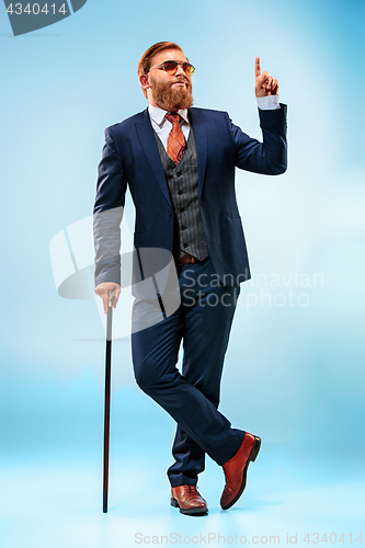 Image of The barded man in a suit holding cane.