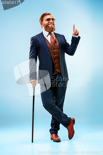 Image of The barded man in a suit holding cane.