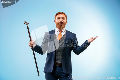 Image of The barded man in a suit holding cane.