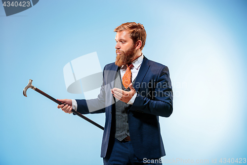 Image of The barded man in a suit holding cane.