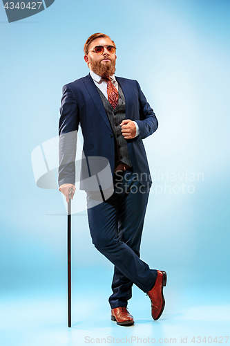 Image of The barded man in a suit holding cane.