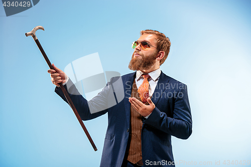 Image of The barded man in a suit holding cane.