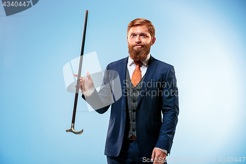 Image of Tattooed bearded man in a suit holding cane.