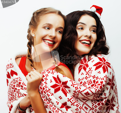 Image of young pretty happy smiling blond and brunette woman girlfriends on christmas in santas red hat and holiday decorated plaid, lifestyle people concept