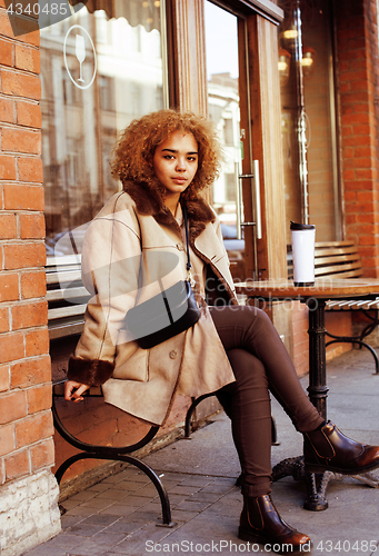 Image of young pretty african american women drinking coffee outside in c