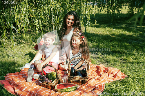 Image of cute happy family on picnic laying on green grass mother and kid