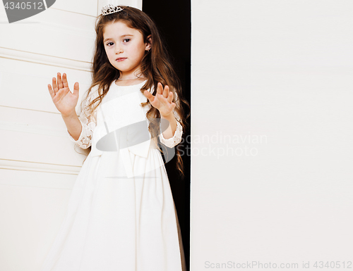 Image of little cute girl at home, opening door well-dressed in white dre