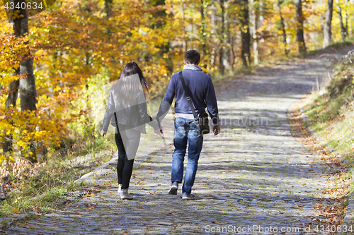 Image of Young couple walking in a park in autumn forest