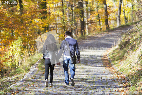 Image of Young couple walking in a park in autumn forest