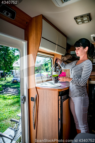 Image of Woman cooking in camper, motorhome interior RV