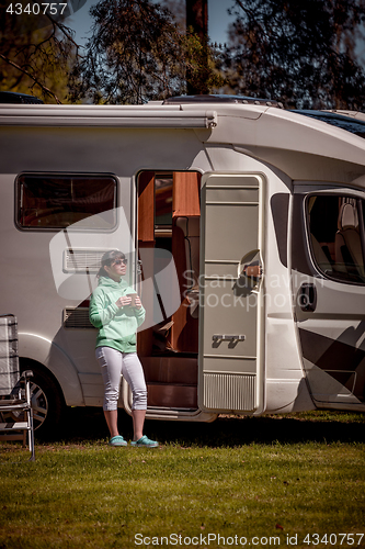 Image of Woman is standing with a mug of coffee near the camper RV.