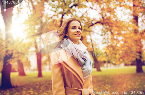 Image of beautiful happy young woman walking in autumn park