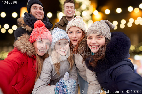 Image of happy friends taking selfie outdoors at christmas