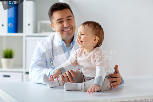 Image of happy doctor or pediatrician with baby at clinic