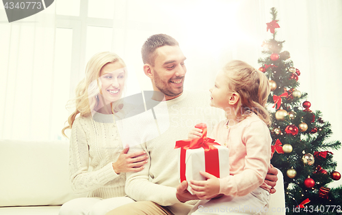 Image of happy family at home with christmas gift