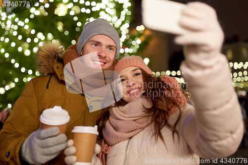 Image of couple with coffee taking selfie at christmas