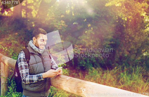 Image of happy man with backpack and smartphone outdoors