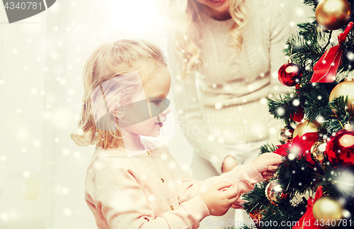 Image of happy family decorating christmas tree at home