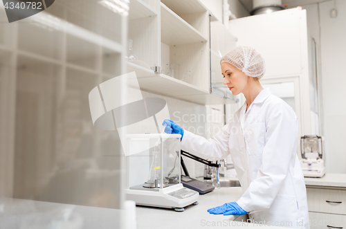 Image of woman with sulphuric acid and scale at laboratory