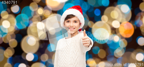 Image of boy in santa hat showing thumbs up at christmas