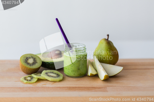 Image of jar with fruit puree or baby food on wooden board