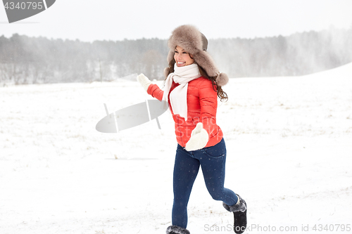 Image of happy woman in winter fur hat having fun outdoors