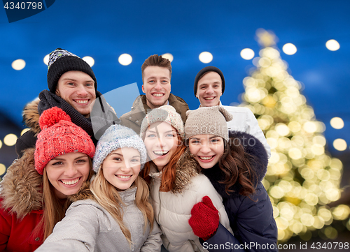 Image of happy friends taking selfie outdoors at christmas