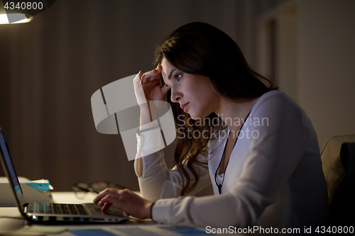 Image of businesswoman with laptop at night office