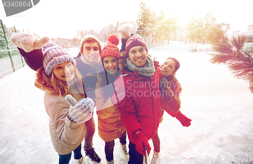 Image of happy friends with smartphone on ice skating rink