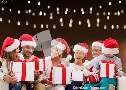 Image of happy family in santa hats with christmas gifts