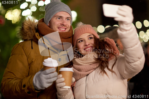 Image of couple with coffee taking selfie at christmas