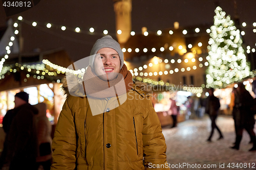 Image of happy young man at christmas market in winter