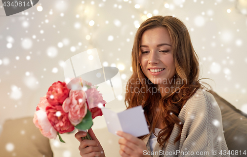 Image of happy woman with flowers and greeting card at home