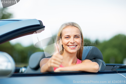 Image of happy young woman in convertible car thumbs up