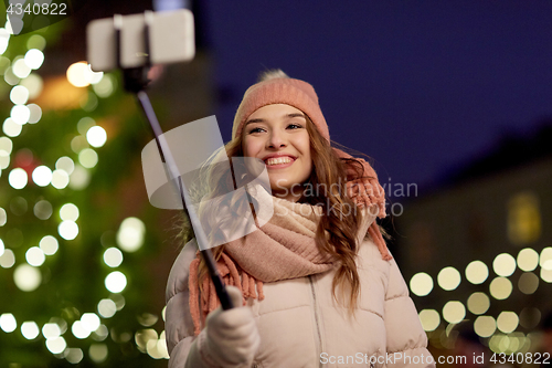 Image of young woman taking selfie over christmas tree