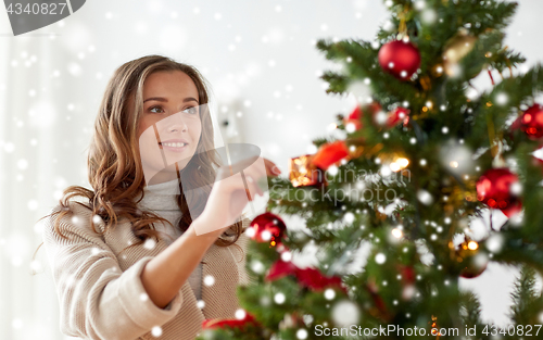 Image of happy young woman decorating christmas tree