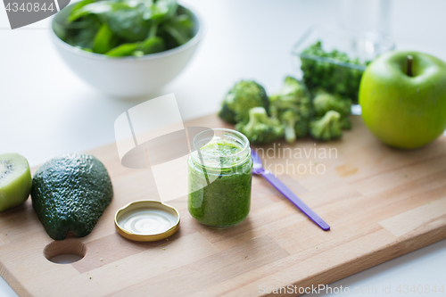 Image of jar with puree or baby food on wooden board