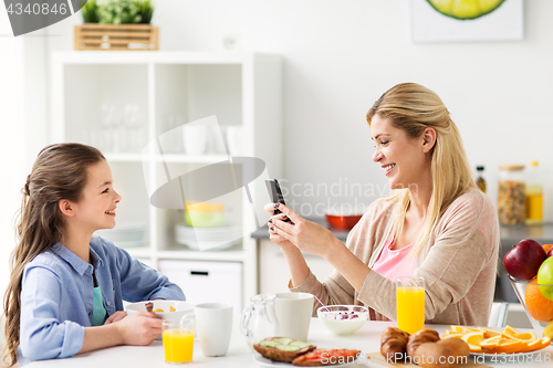 Image of family with smartphone having breakfast at home