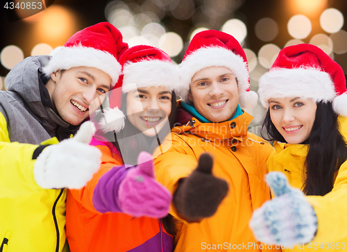 Image of happy friends in santa hats and ski suits outdoors