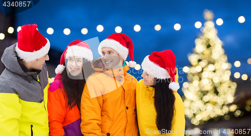 Image of friends in santa hats and ski suits at christmas