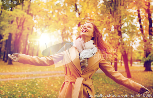 Image of beautiful happy young woman walking in autumn park