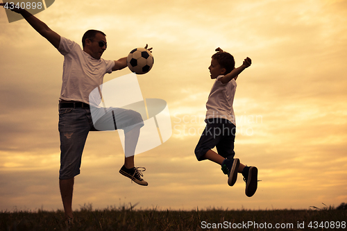 Image of Father and young little son playing in the field  with soccer ba