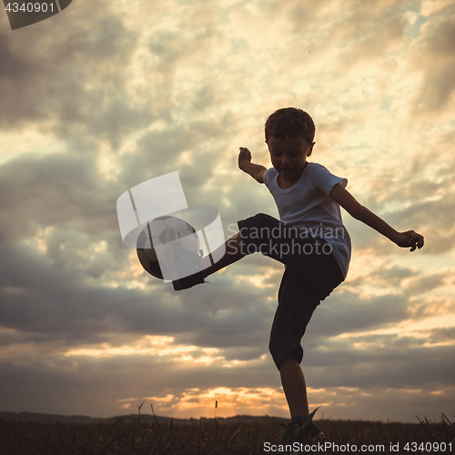 Image of Young little boy playing in the field  with soccer ball.