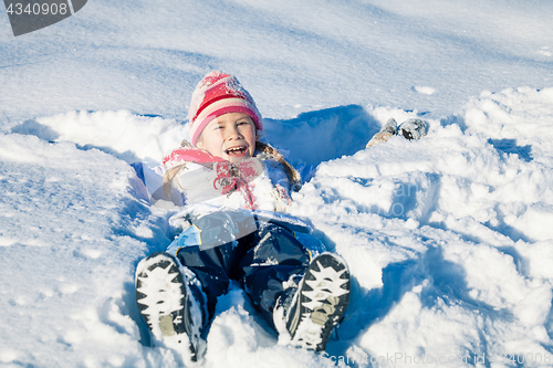 Image of Happy little girl playing  on winter snow day.