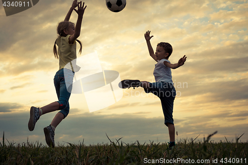 Image of Happy young little boy and girl playing in the field  with socce