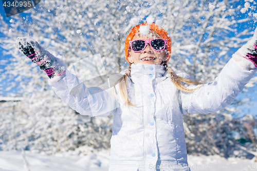 Image of Happy little girl playing  on winter snow day.