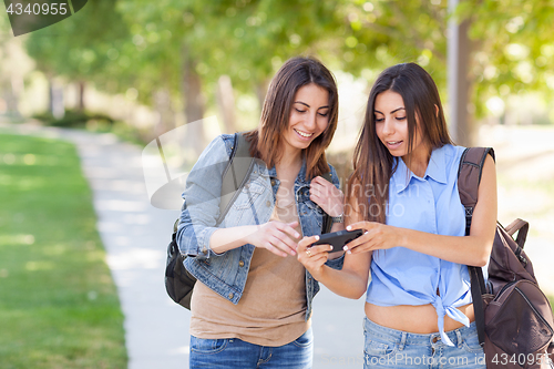 Image of Two Beautiful Young Ethnic Twin Sisters With Backpacks Using A S