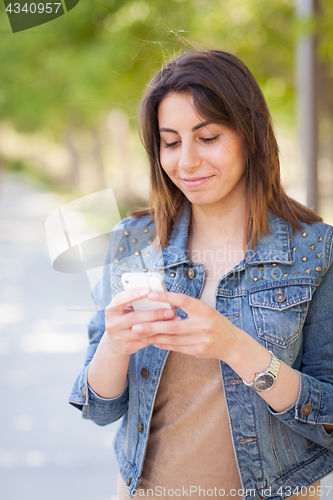 Image of Beautiful Young Ethnic Woman Using Her Smartphone Outside.