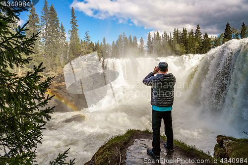 Image of Nature photographer tourist with camera shoots while standing Ri